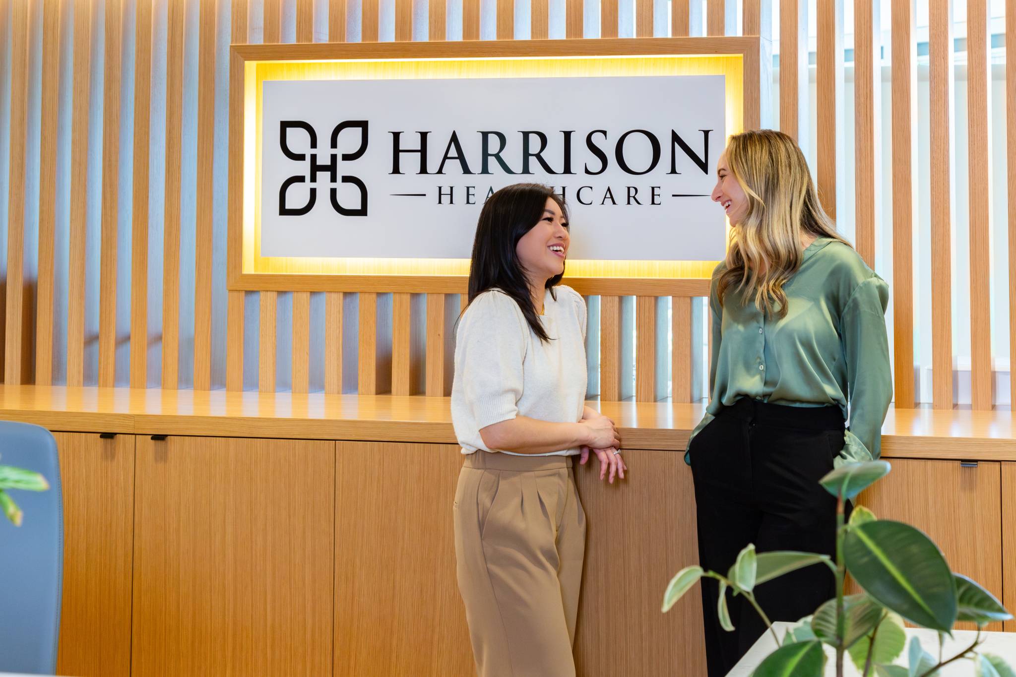 two women smiling with eachother at front desk