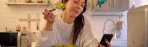 Woman eating salad while distracted on phone